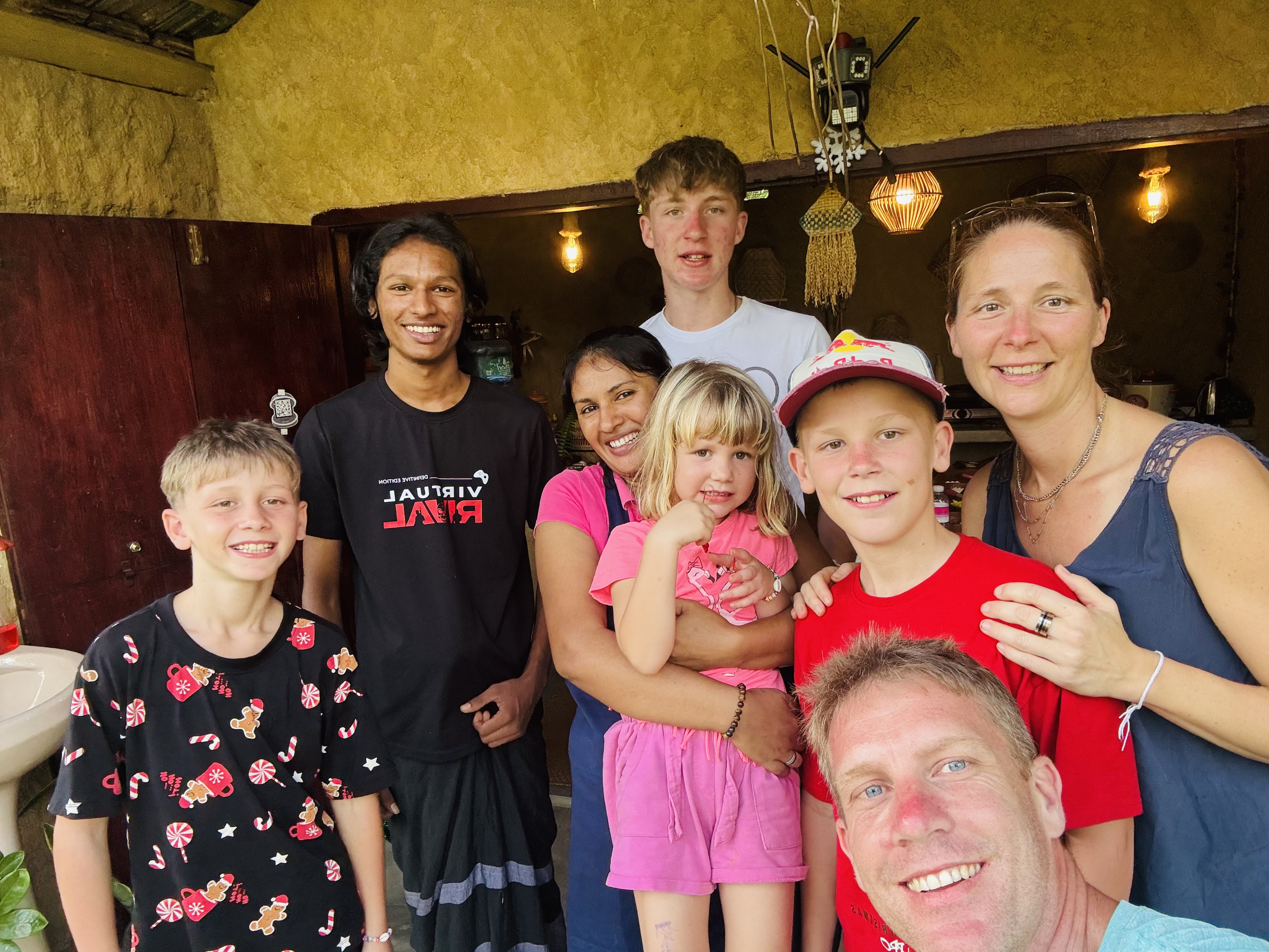Happy cooking class graduates posing for a group selfie with Chef Priya and her son